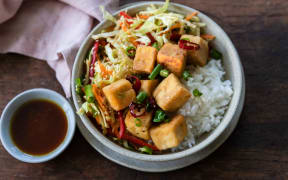 A round bowl of salt and pepper tofu cubes, served with slaw and rice.