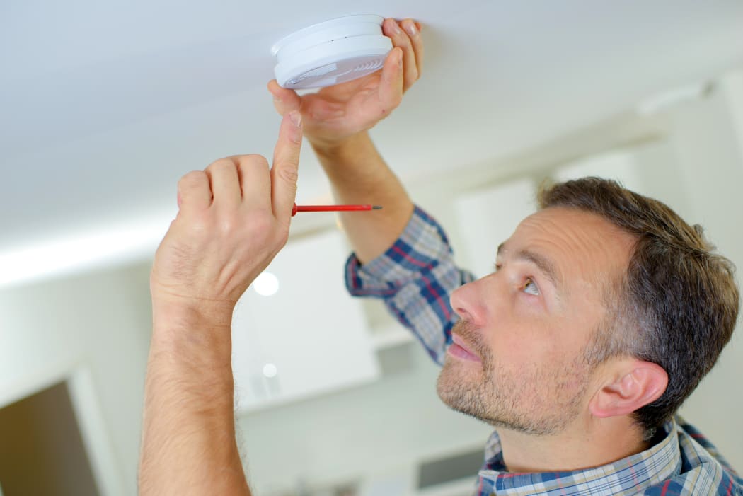 File image of man installing a smoke alarm.