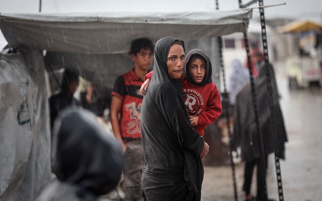 A displaced Palestinian woman pushes water away from her tent after heavy rainfall at a makeshift camp inside Gaza's port during a rainstorm in Gaza, Palestine, on Friday.