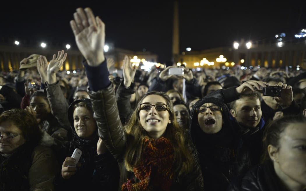 Faithfuls react as Argentina's cardinal Jorge Bergoglio, elected Pope Francis I appears on the balcony of St Peter's Basilica's after being elected the 266th pope of the Roman Catholic Church on March 13, 2013 at the Vatican. Argentina's Jorge Mario Bergoglio was elected Pope Francis I on Wednesday, becoming the church's first Latin American pontiff after a conclave to elect a leader of the world's 1.2 billion Catholics.    AFP PHOTO / JOHANNES EISELE (Photo by JOHANNES EISELE / AFP)