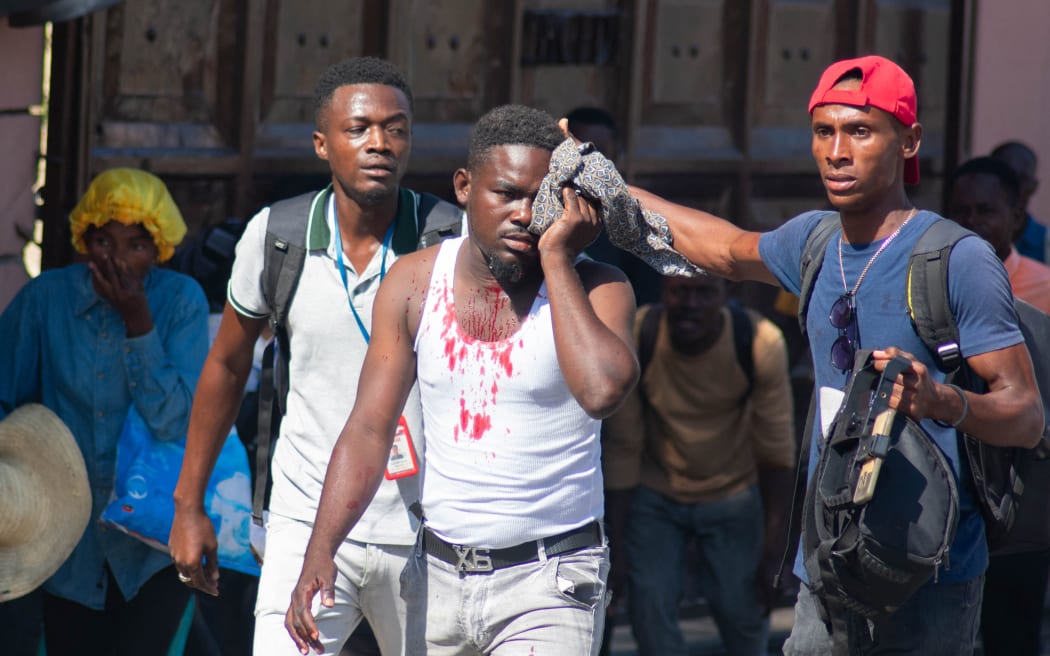 An injured journalist is helped after he was reportedly hit by a tear gas canister fired by police in Port-au-Prince, Haiti, on March 9, 2024. Sporadic gunfire rang out in Port-au-Prince late March 8, an AFP correspondent there heard, as residents desperately sought shelter amid the recent explosion of gang violence in the Haitian capital. (Photo by Clarens SIFFROY / AFP)