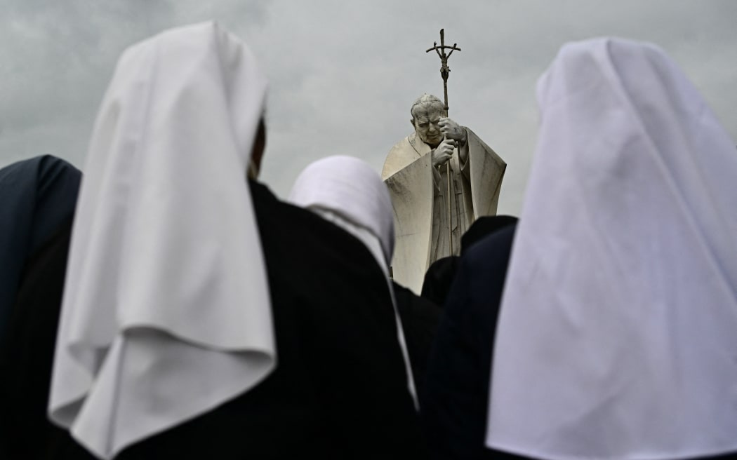 Nuns pray at the statue of John Paul II outside the Gemelli University Hospital where Pope Francis is hospitalized with pneumonia, in Rome on March 01, 2025. Pope Francis, hospitalised for two weeks with pneumonia in both lungs, spent a peaceful night after suffering a breathing crisis, the Vatican said on March 01, 2025. (Photo by Tiziana FABI / AFP)