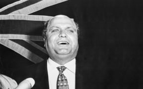 Mike Moore in front of flag, 1993