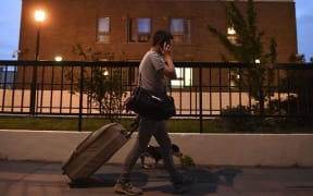 A resident talks on a mobile phone as he leaves the Burnham Tower residential block on the Chalcots Estate in north London on June 23, 2017 after being evacuated because of fire safety concerns.