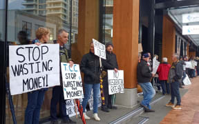 Some of the 60 people that gathered outside the Tauranga City Council building to protest the 9.9% rates increase on Thursday morning.