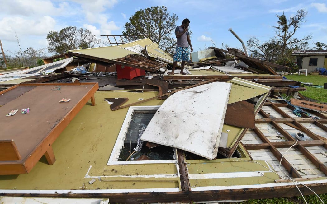 A Port Vila resident looks through the ruins of his home.