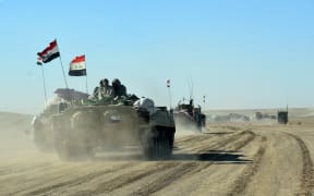 Members of the Iraqi forces and the Hashed al-Shaabi (Popular Mobilisation units) ride on infanty-fighting vehicles near the Iraqi-Syrian border