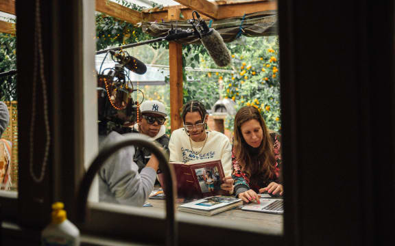 (L-R) Beto, Jamil, and Mara looking at old photo albums while being filmed