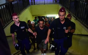 Hungarian police escort refugees from a train they boarded in the hope of reaching western Europe.