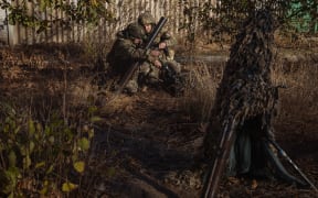 Ukrainian servicemen of the 123rd Territorial Defense Brigade prepare to fire a mortar over the Dnipro River toward Russian positions, in an undisclosed location in the Kherson region, on November 6, 2023, amid the Russian invasion of Ukraine. While Ukraine's recapture of Kherson city last November was a shock defeat for the Kremlin, Russian forces on the opposing bank still control swathes of territory and shell towns and villages they retreated from. The Dnipro, Europe's fourth-longest river and a historic trading route, has become a key front since Ukrainian troops pushed Russian forces back over its banks in the south last year. (Photo by Roman PILIPEY / AFP)