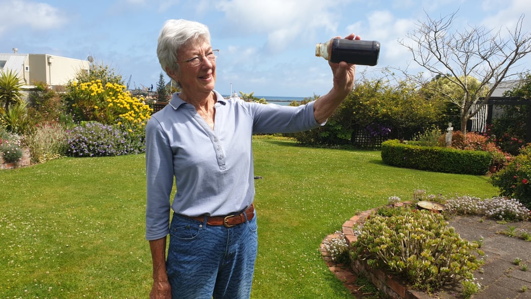 Daveena Dawrant, from New Plymouth, holds a jar of oil, which was collected from an abandoned well underneath her backyard.