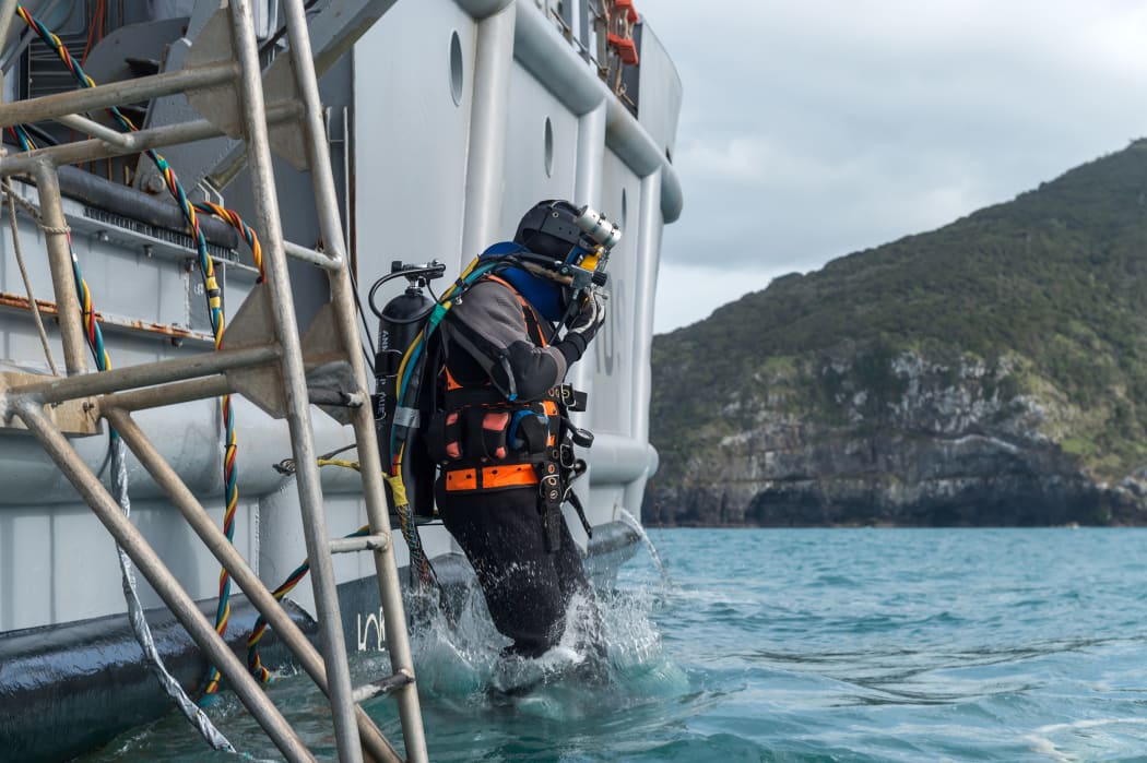 Navy diver Luke Gordon enters the water in Akaroa Harbour from HMNZS Manawanui during training ahead of a search and recovery operation at the site of sunken fishing vessel Jubilee on 26 October 2015.
