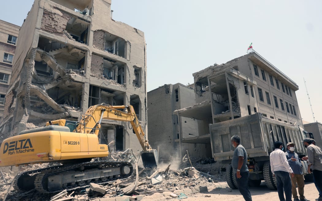 An excavator is used to clear the rubble in front of a building recently hit in Israeli strikes in Tehran on June 26, 2025, following a ceasefire with Israel that ended 12 days of fighting. (Photo by AFP)