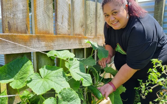 Te Rina Waiwiri shows a cucumber growing in her garden.