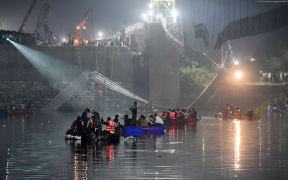 Indian rescue personnel conduct search operations after a bridge across the river Machchhu collapsed in Morbi, some 220 kms from Ahmedabad, early on October 31, 2022. - At least 75 people were killed on on October 30 in India after an almost 150-year-old colonial-era pedestrian bridge collapsed, sending scores of people tumbling into the river below. (Photo by SAM PANTHAKY / AFP)