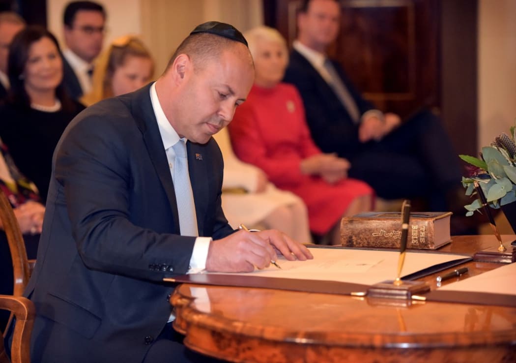 Australian Treasurer Josh Frydenberg signs a document during an oath-taking ceremony at Government House in Canberra on May 29, 2019.