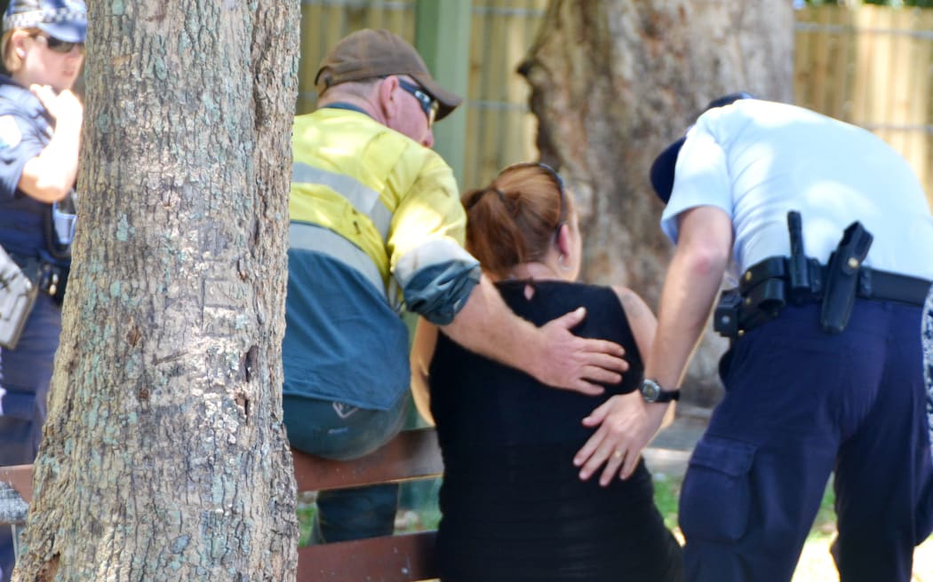 Police comfort a woman near the home in Manoora where the children were found dead.