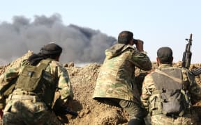 Turkish-backed Syrian rebels watch the border town of Ras al-Ain on October 12, 2019, during their assault on Kurdish-held border towns in northeastern Syria.