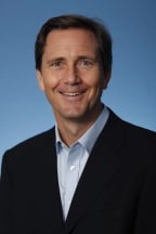English academic and writer Richard Reeves smiles in front of a blue background