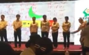 The video, posted by People's Daily, shows a trainer spanking employees of a Chinese bank with what appears to be a stick.