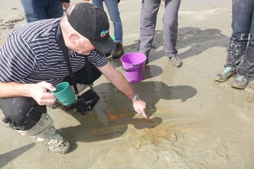 Greg Browne points at a dinosaur footprint