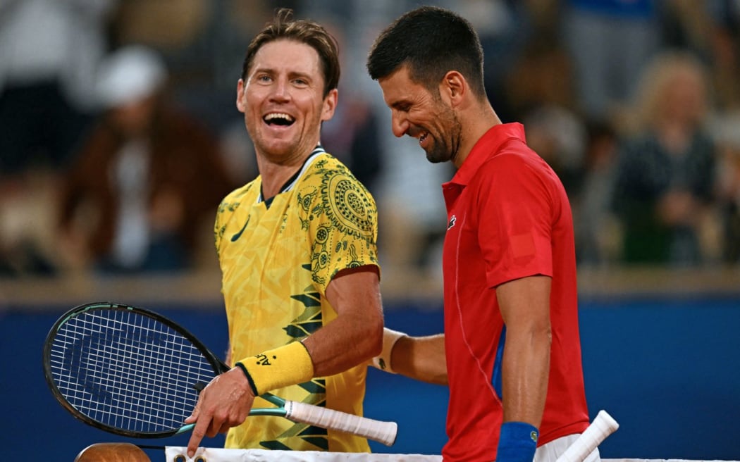 Serbia's Novak Djokovic (R) shares a joke with Australia's Matthew Ebden (L) after their men's singles first round tennis match on Court Philippe-Chatrier at the Roland-Garros Stadium at the Paris 2024 Olympic Games, in Paris on July 27, 2024. (Photo by PATRICIA DE MELO MOREIRA / AFP)