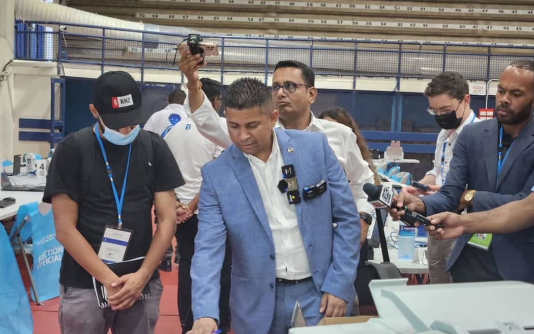 Fiji's supervisor of elections, Mohammed Saneem, (in suit) walks media through the main counting centre in the capital Suva. 14 December 2022
