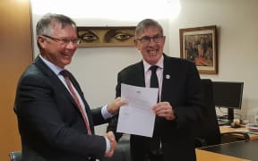 Trade Minister David Parker receiving a note from the Australian High Commissioner Ewen McDonald confirming Australia's ratification.