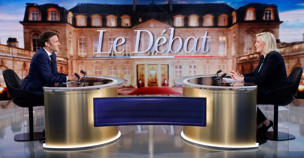 French President Emmanuel Macron (L) and French far-right party Rassemblement National (RN) candidate Marine Le Pen (R) sit prior to taking part in a live televised debate on French TV
