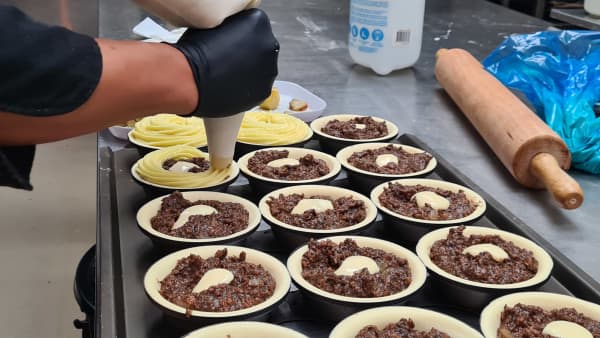 Samraksmey (Sam) So, owner of Rosedale Bakery & Café, piping the potato tops onto the mince pies at his bakery's kitchen.