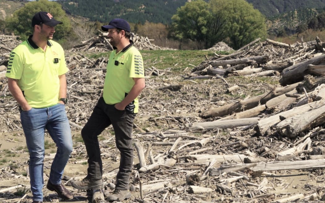Aratu's tree crop manager Willy Grogan, left, and cyclone recovery manager Rich Powell, right, standing amid the windrows of slash on Paroa Station.