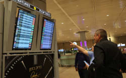 Passengers look at a departure board at Ben Gurion Airport near Tel Aviv, Israel, on October 7, 2023, as flights are canceled because of the Hamas surprise attacks. The conflict sparked major disruption at Tel Aviv airport, with American Airlines, Emirates, Lufthansa and Ryanair among carriers with cancelled flights.