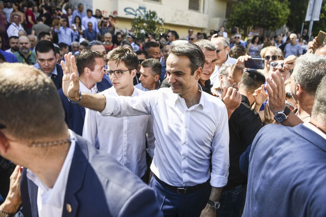 Greece's opposition party New Democracy leader Kyriakos Mitsotakis (centre) greets supporters as he leaves a polling station after casting his vote during general elections in Athens on 7 July, 2019.