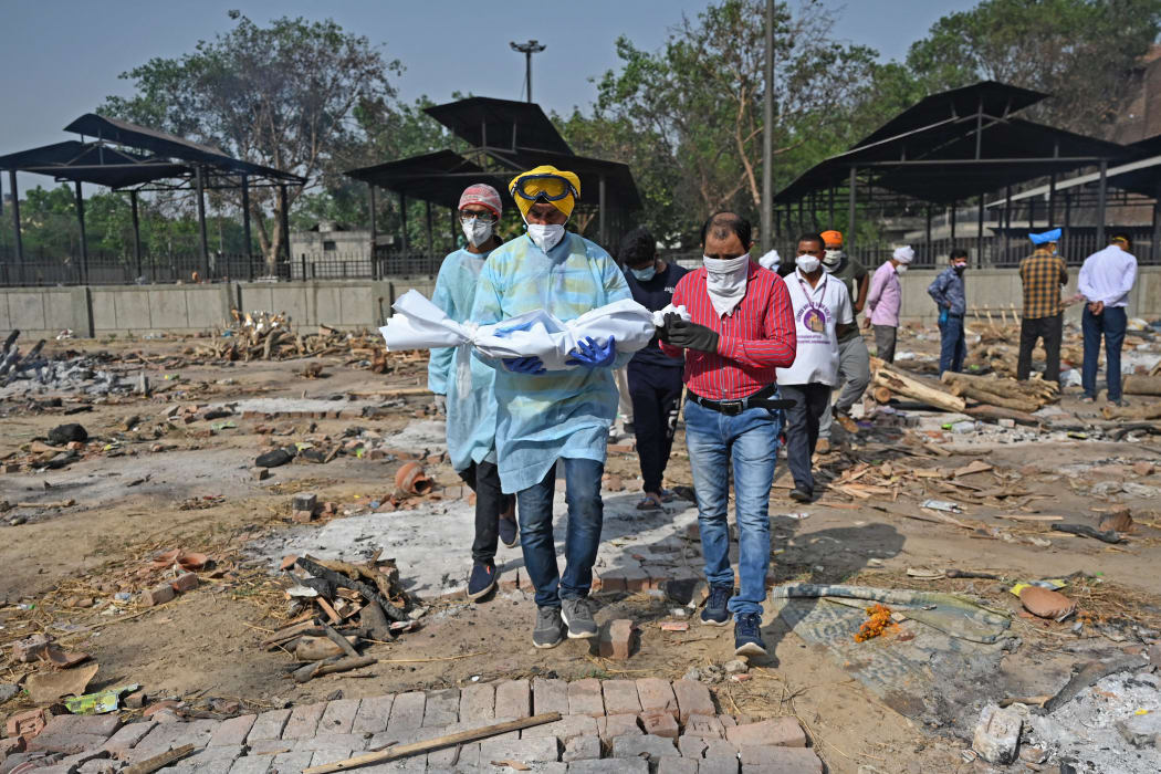 A volunteer carries the body of a child who died of Covid-19 for the last rites at a crematorium in New Delhi, on 12 May.