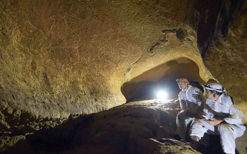 The Cultural Heritage Service Manager of the Provincial Council of Biscay, Andoni Iturbe (L) and professor of Prehistory, Cesar Gonzalez (R) look at cave engravings representing animals like horses, bisons, lions or goats, in the Armintxe cave in Lekeitio.