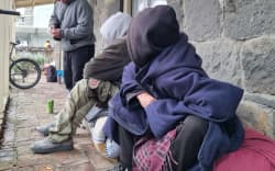 A group of homeless people sheltering under the verandah of the earthquake-prone Richmond Cottage in New Plymouth.