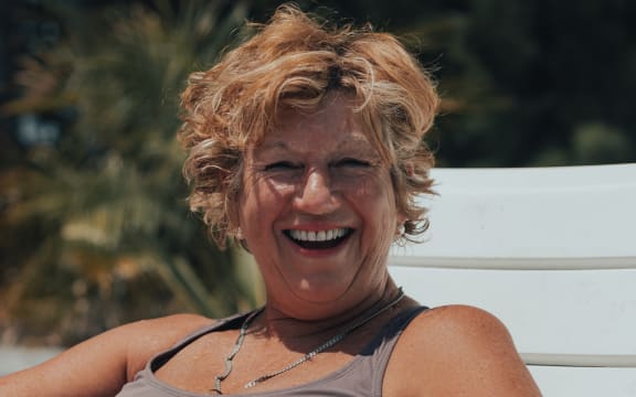 A happy older woman sitting outside in the sun.