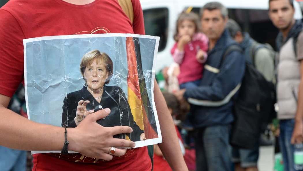 A refugee holds a picture of German Chancellor Angela Merkel after the arrival of refugees at the main train station in Munich, southern Germany, September 05, 2015.