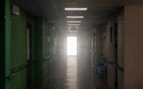 blurred dark hospital corridor with a luminous door at its end - an allegory of clinical death