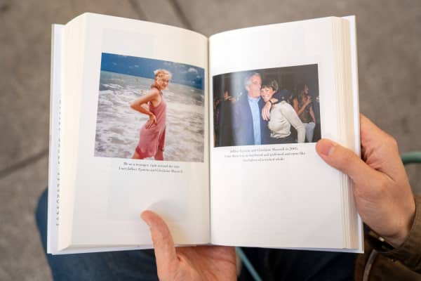 A person holds open pages of the book "Nobody's Girl - A Memoir of Surviving Abuse and Fighting for Justice" by Virginia Roberts Giuffre, displaying photos published in the book, as it is pictured in central London on October 21, 2025, on the day of its release in the UK.