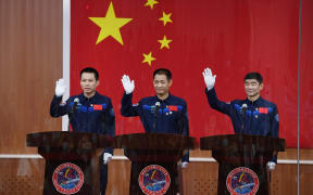 Astronauts Nie Haisheng (centre), Liu Boming (right) and Tang Hongbo wave as they arrive for a briefing the day before their launch in China on 16 June, 2021.