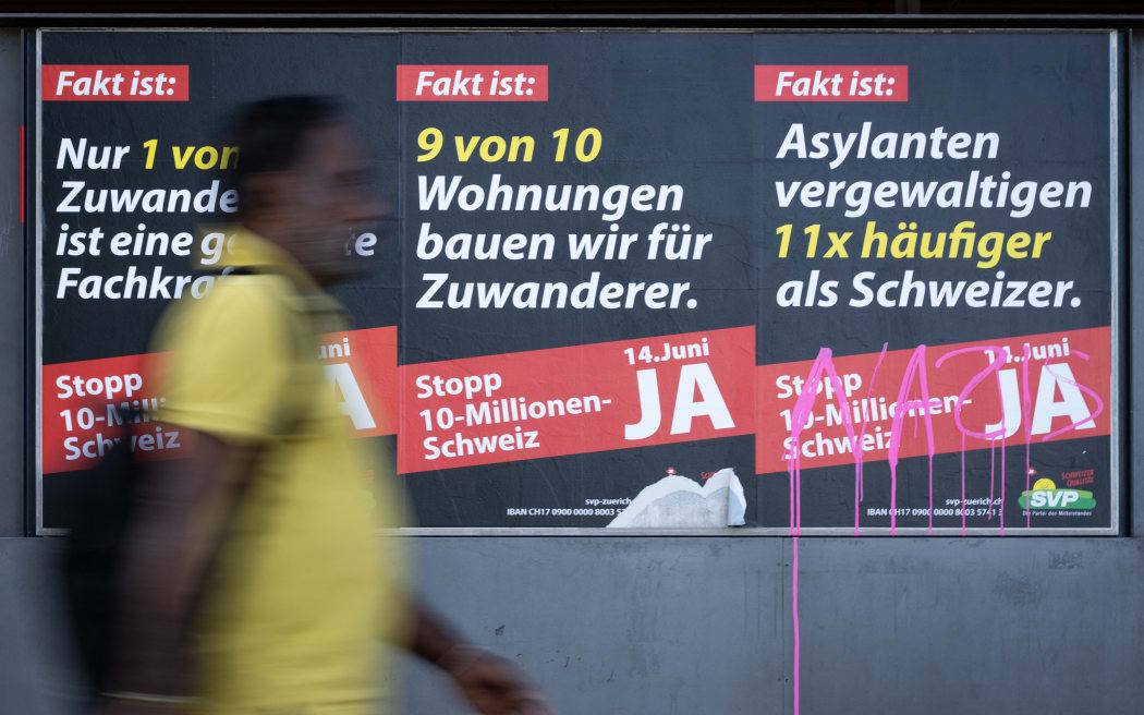 A man passes by posters campaigning for the “yes” vote at next June 14’s initiative launched by the hard-right Swiss People’s Party (SVP) to cap the population at 10 million, an anti-immigration proposal that is fracturing public opinion in the wealthy Alpine nation, in Zurich on May 28, 2026. The panels slogans read in German (from L) : “The fact is: Only 1 in 10 immigrants is a skilled worker in demand”, “The fact is: We build 9 out of 10 homes for immigrants” and “The fact is: Asylum seekers commit rape 11 times more often than Swiss nationals” (Photo by SEBASTIEN BOZON / AFP)