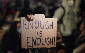 A person holds up a sign as protesters kneel on Canal St during a demonstration over the death of George Floyd in police custody in Minneapolis.