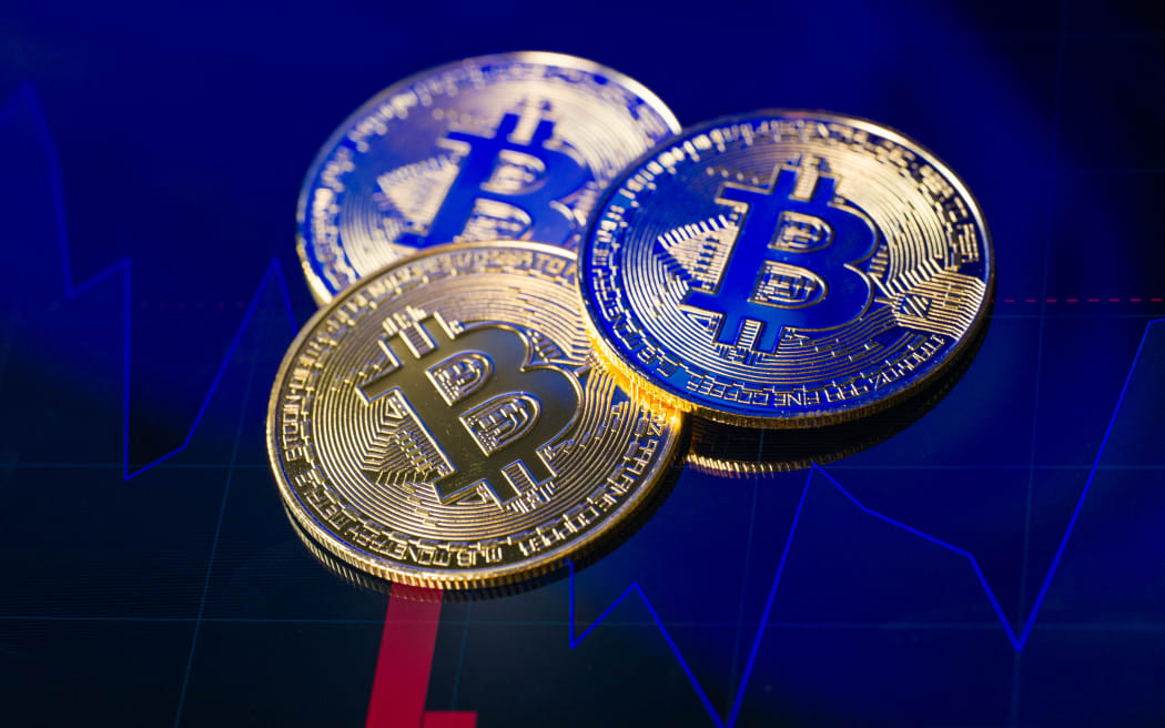 Tokens representing Bitcoin are placed on a screen showing a declining cryptocurrency chart, as Bitcoin trades around $89,635 against the U.S. dollar, in this photo illustration in Brussels, Belgium, on December 6, 2025. (Photo by Jonathan Raa/NurPhoto) (Photo by Jonathan Raa / NurPhoto via AFP)