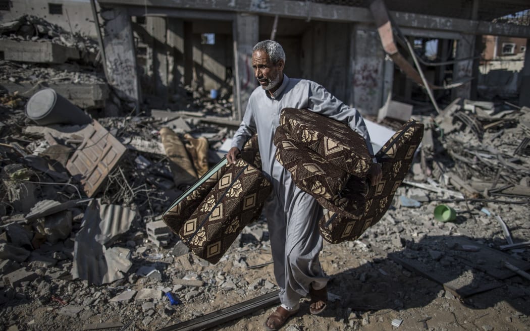 A Palestinian salvages cushions found in the rubble of destroyed buildings  in the Shejaiya residential district of Gaza City.