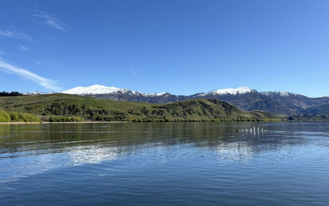 Lake Hayes on a clam sunny day with snow-dusted mountains in the background