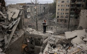 A volunteer gesticulates on top of a partially destroyed residential building after a shelling in Sloviansk, Donetsk region on April 14, 2023.