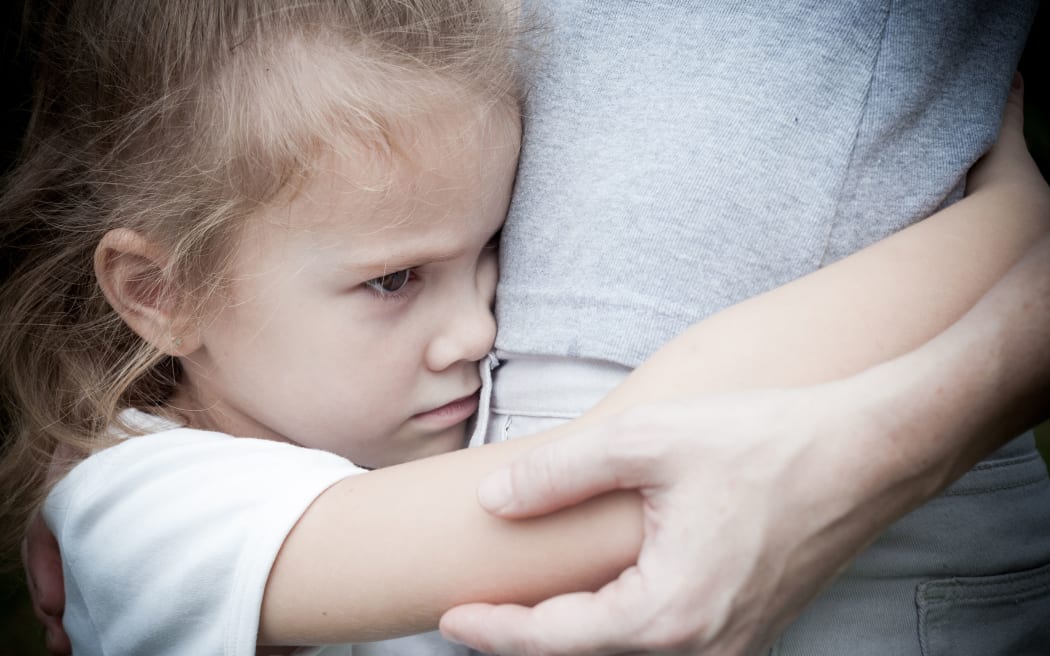 A photo of a sad looking daughter hugging her mother around the waist