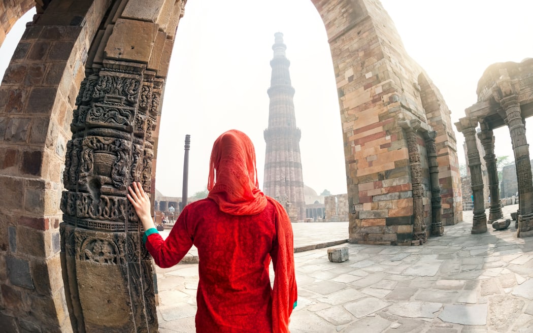 A woman looking at Qutab Minar tower in Delhi, India