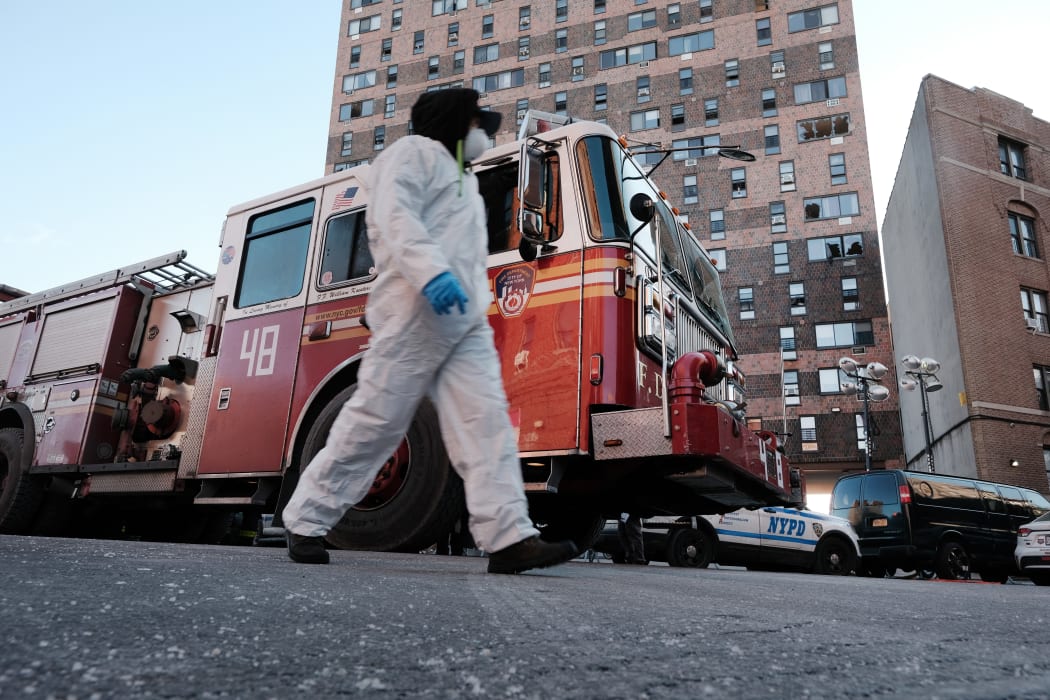 A clean-up and recovery worker walks in front of a Bronx apartment building a day after a fire swept through the complex killing at least 17 people.